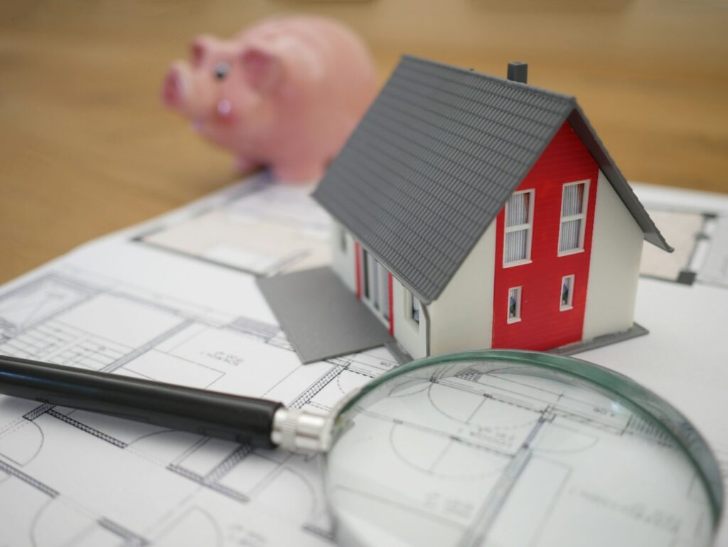 House model beside a magnifying glass – using home equity to build wealth