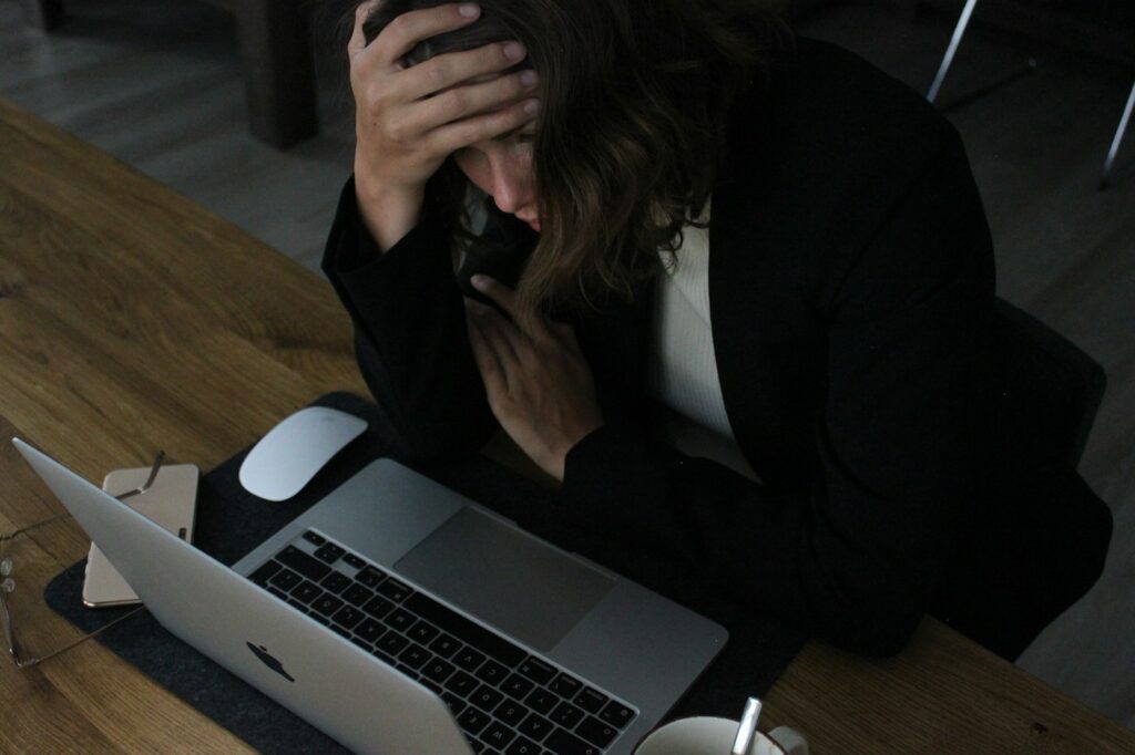 Stressed woman with her head in her hands at a laptop – how bad financial decisions affect your credit