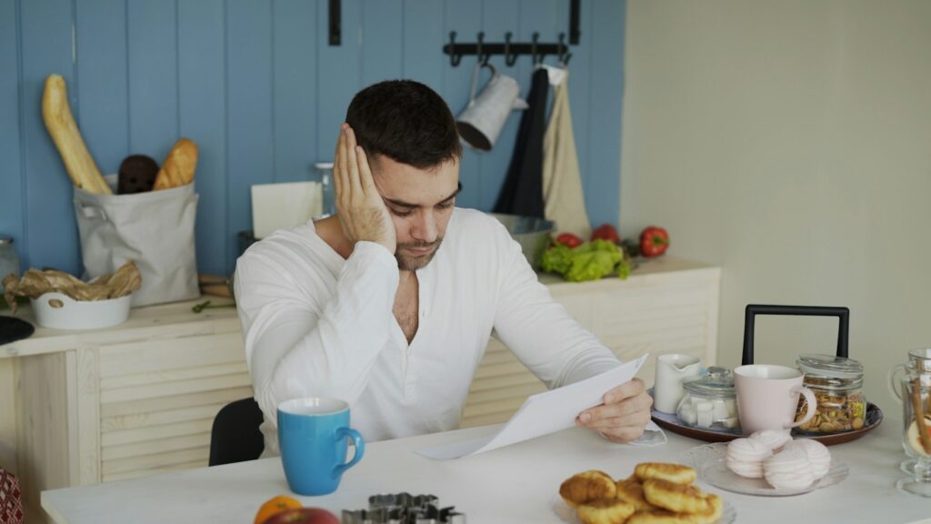 Man reading paperwork at the kitchen table – avoiding a last-minute mortgage denial