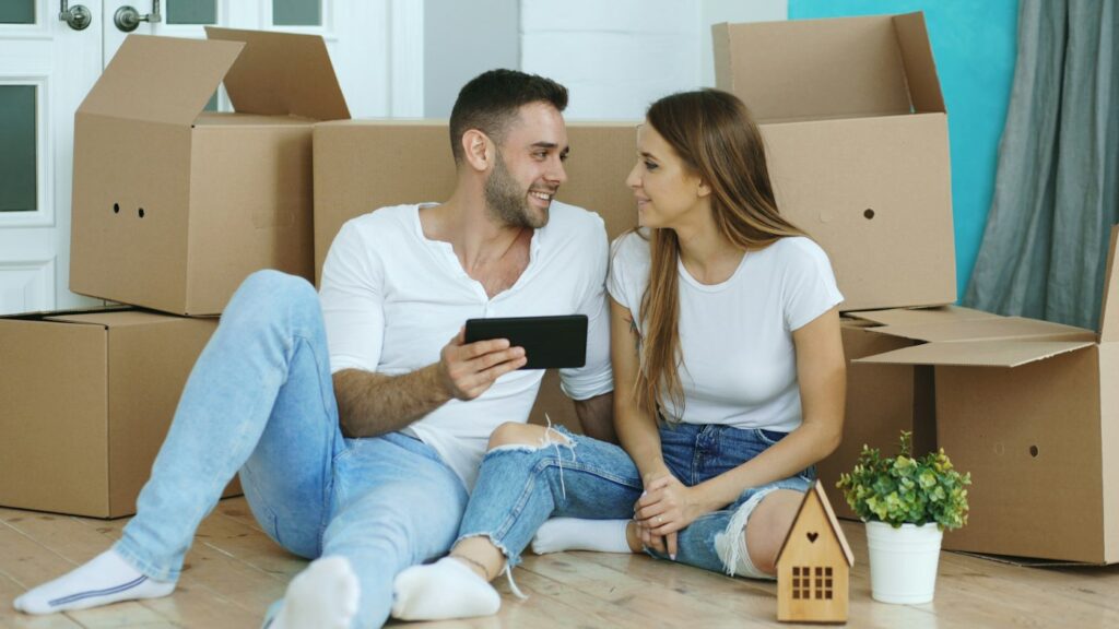 Couple surrounded by moving boxes in their new home – mortgage success stories