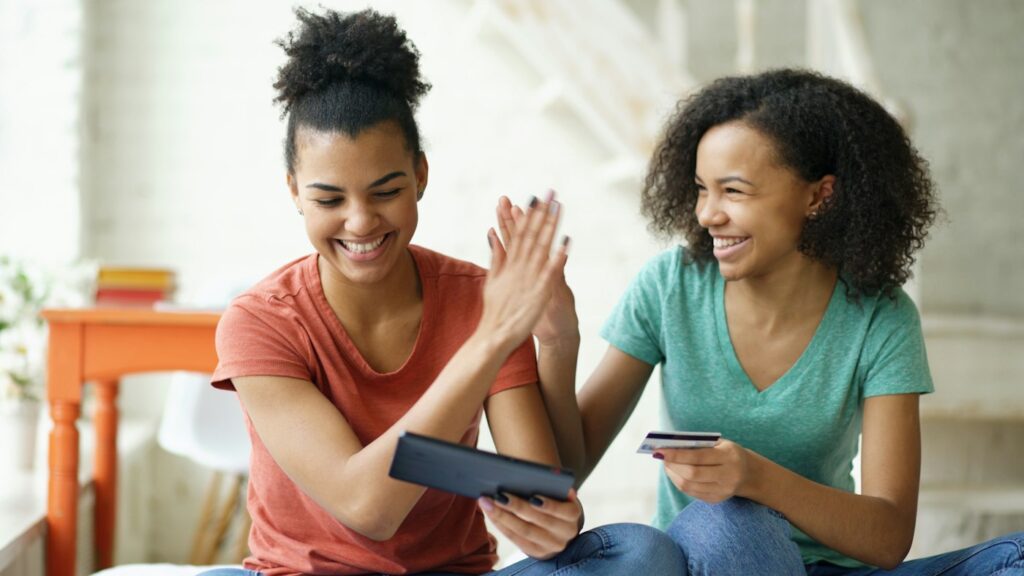 Two women high-fiving at a laptop – boosting your credit score for mortgage approval